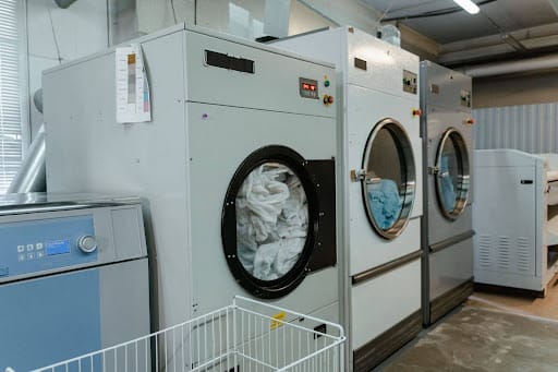 Commercial laundry machines cleaning sports uniforms for professional team laundry service.